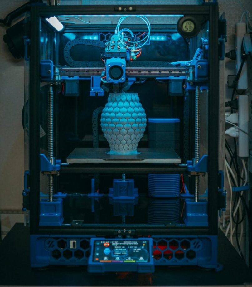 Close-up of a 3D printer in action, crafting a detailed vase in a modern setting.